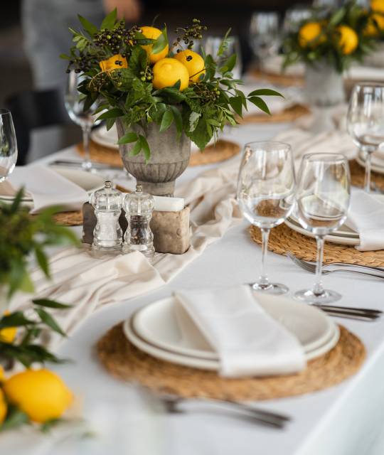 Festive table at the wedding party are decorated with lemon arrangements, on the table are plates with napkins and glasses